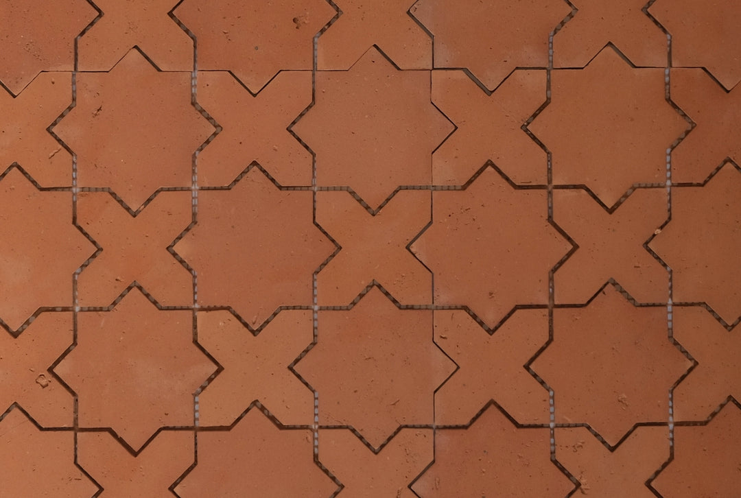 Pattern of star and crossed shaped terracotta tiles arranged in a grid.