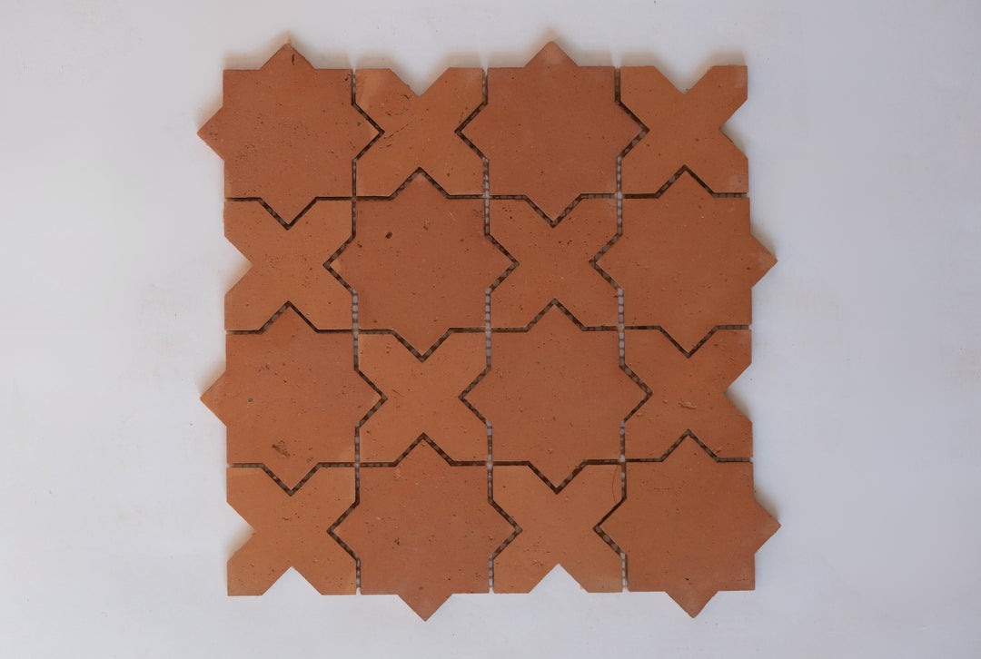Terracotta tiles with star-and-cross shaped cutouts on a white background