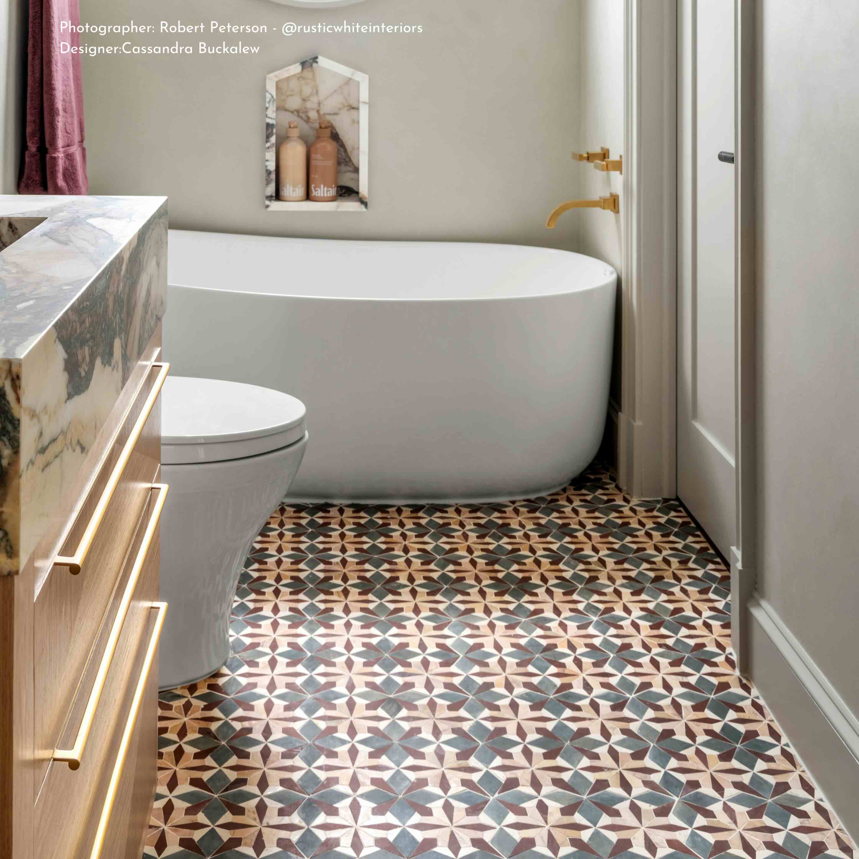 Modern bathroom with freestanding bathtub, patterned floor, and wooden vanity.