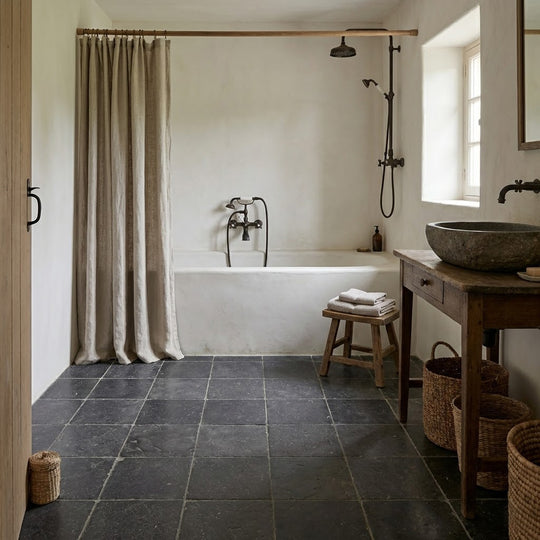 Bathroom with dark tiled floor, white bathtub, and wooden vanity.