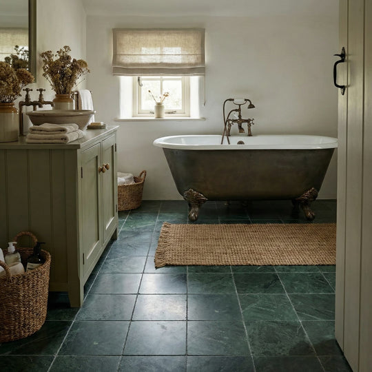 Bathroom with a freestanding bathtub, dark green tiled floor, and sage green wooden vanity.