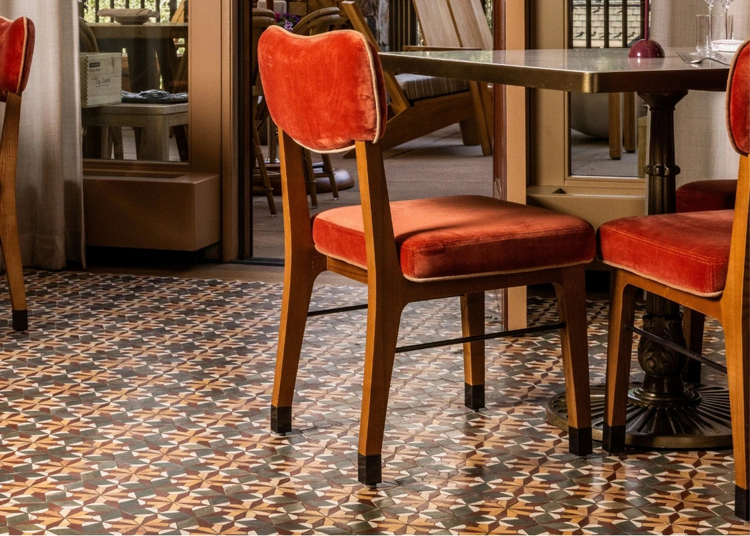 Dining area with red cushioned chairs and a patterned floor, leading to an outdoor patio.
